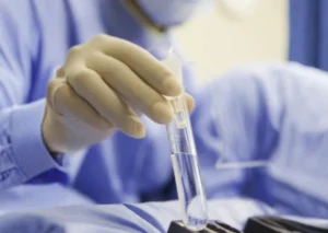 Gloved scientist holding a test tube during laboratory processing for how long does ivf take in singapore.