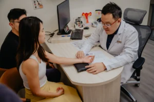 Doctor examining a patient's pulse during a consultation on IVF success rate Singapore.